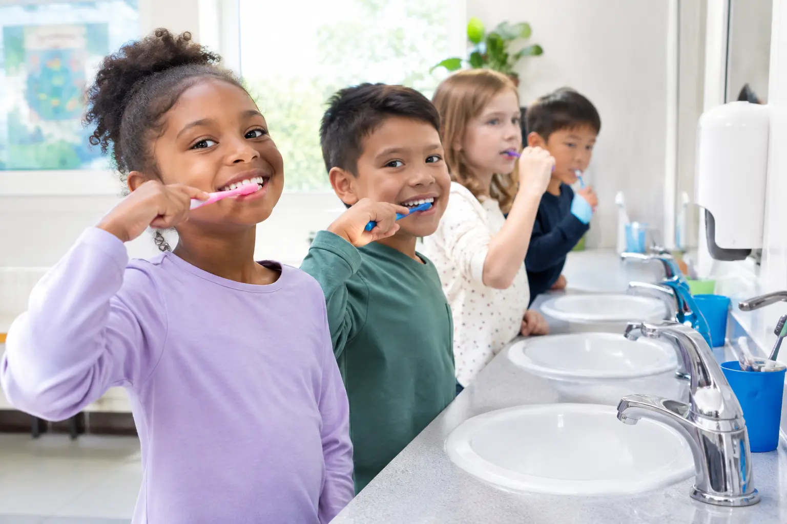 Fila de niños de escuela primaria cepillándose los dientes durante una jornada de educación en higiene oral