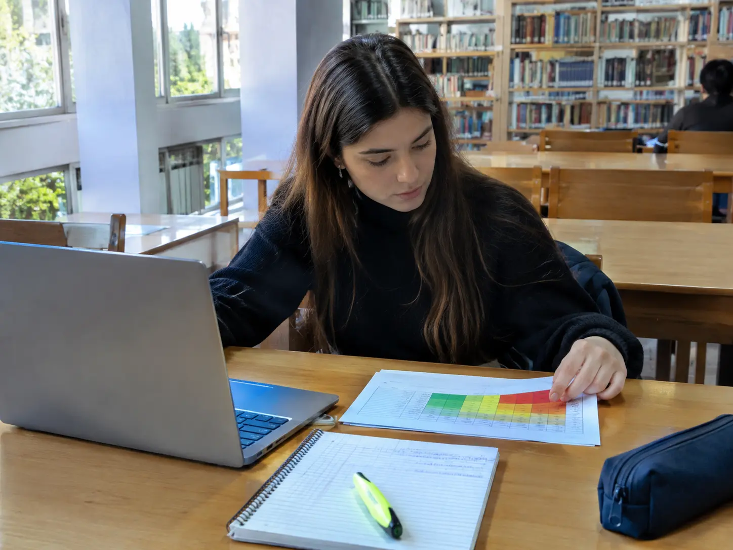Estudiante de Contador Público armando una matriz de riesgos con celdas de colores en una biblioteca